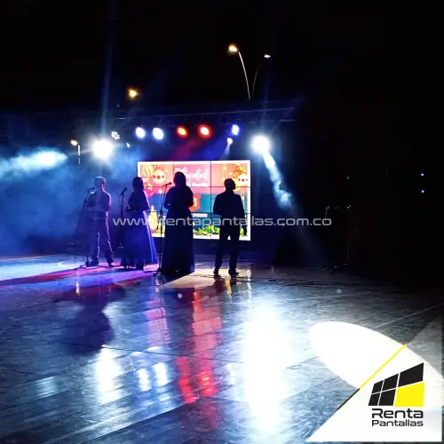 Equipo de alquiler de sonido profesional con torres iluminadas con luces LED, pantalla LED frontal y máquina de humo en funcionamiento.